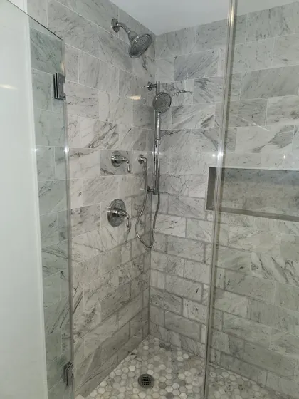 Walk-in tiled shower with glass door and Kohler fixtures